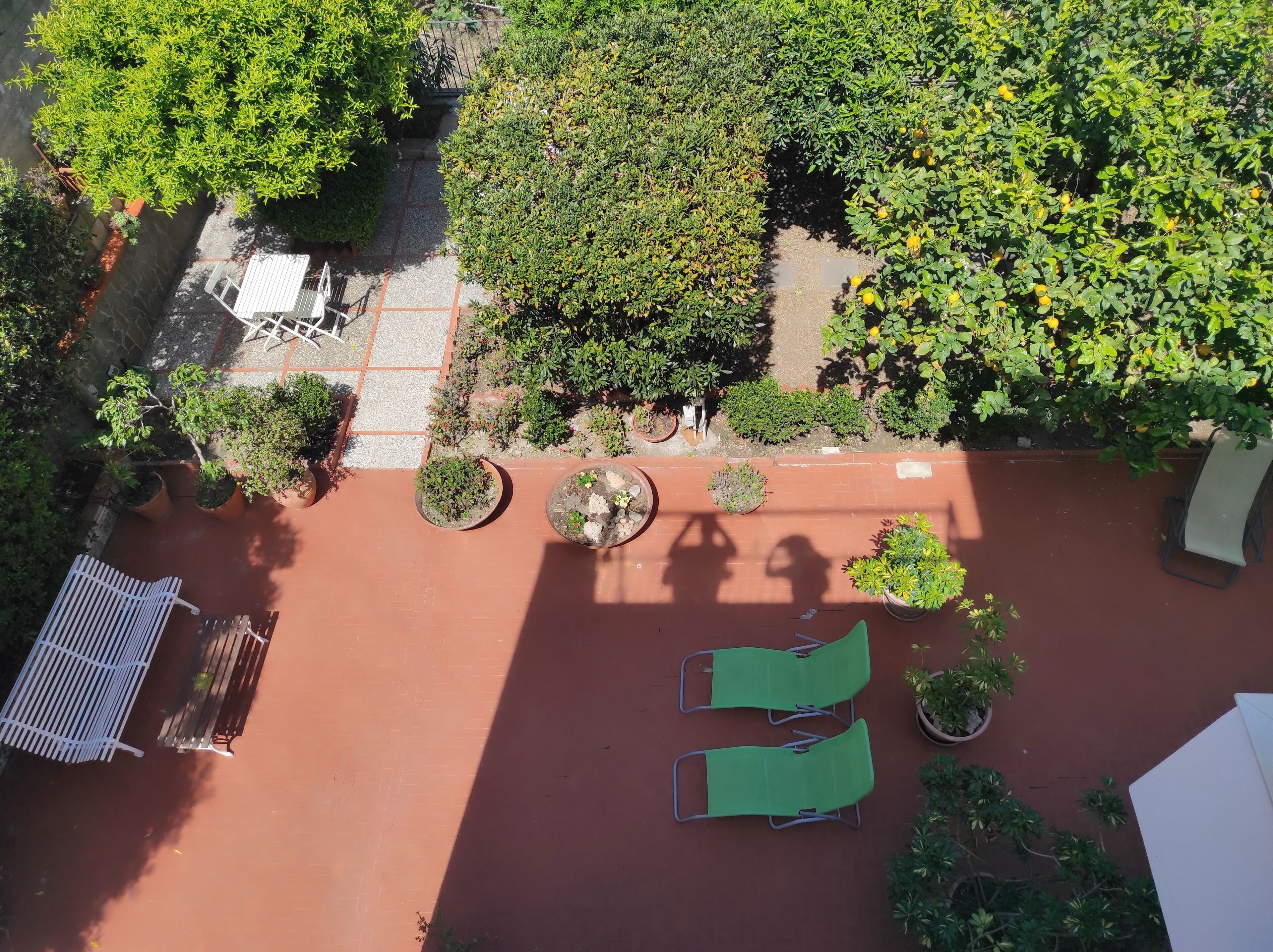 An aerial view of a courtyard with potted plants, a small pool, and two green lounge chairs.