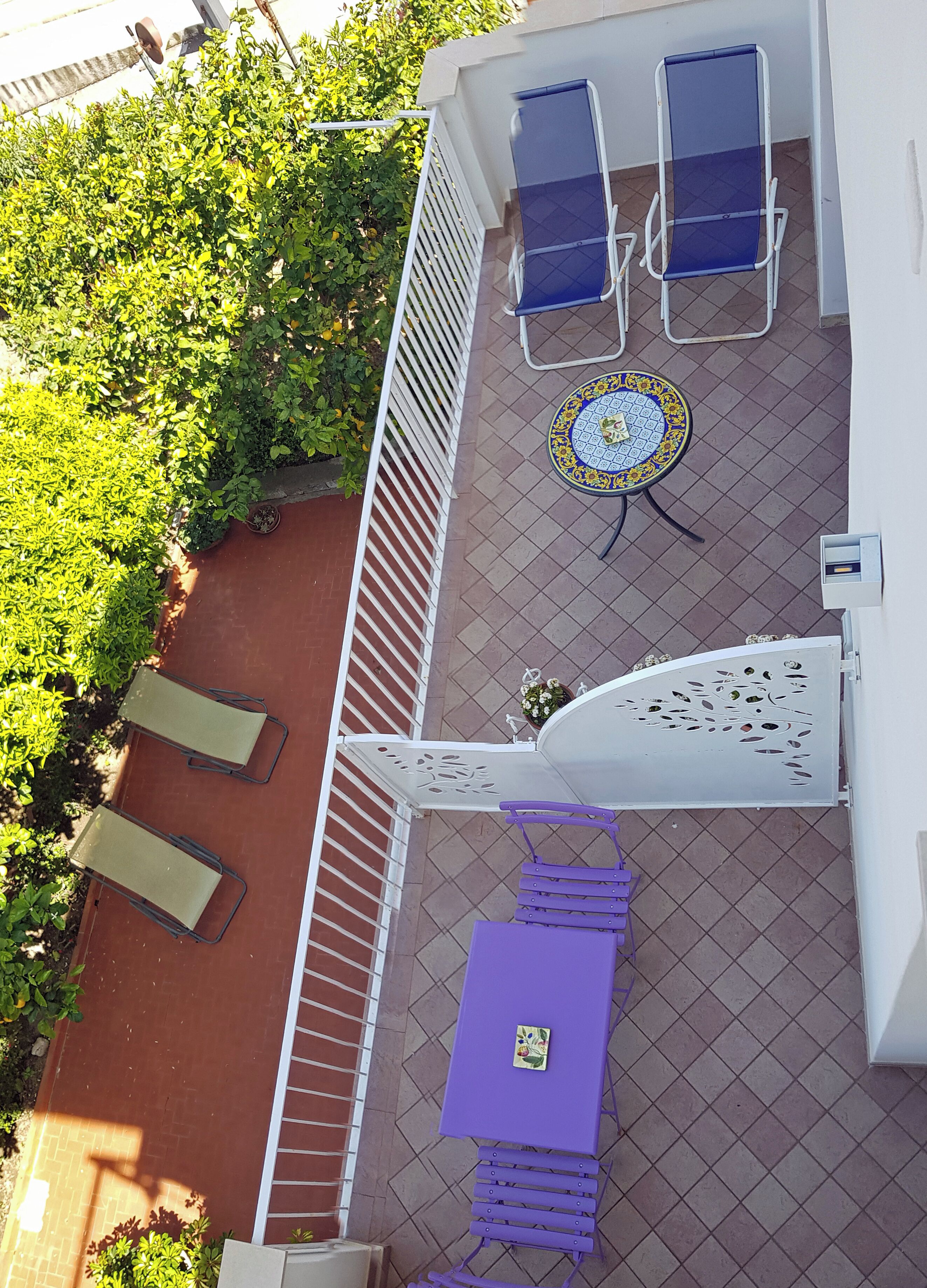 Une terrasse extérieure avec une table et des chaises, un mur décoratif et une rambarde.