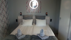 A double bed with two pillows, a bedside table with a lamp, and a wall-mounted mirror. - Kvarngården Natur Resort (Byxelkrok)