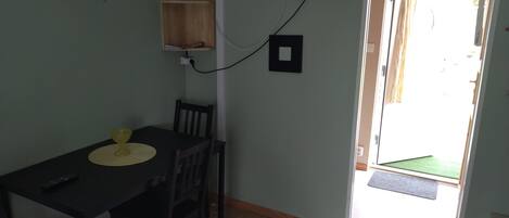 Un comedor con una mesa, sillas, un televisor montado en la pared y una puerta que da al exterior.