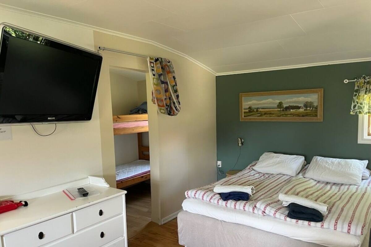 Un dormitorio con una cama, televisor, cómoda y literas.