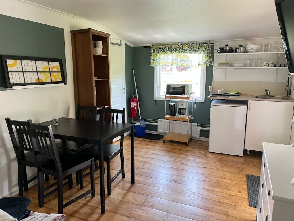 A compact kitchen with a dining table, chairs, a microwave, and a small refrigerator.