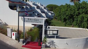 Un edificio con un cartel que dice "Bacchus Restaurante" y una alfombra roja que lleva a la entrada.