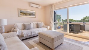 Una sala de estar moderna con un sofá, un reposapiés y un comedor con sillas y una mesa.
