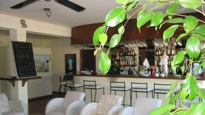 Un restaurante con zona de bar, sillas blancas tapizadas y un ventilador de techo.