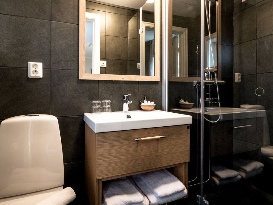A modern bathroom with a white sink, wooden vanity, and a glass shower enclosure.