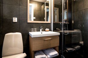 A modern bathroom with a white sink, wooden vanity, and a glass shower enclosure.