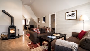 A cozy living room with a fireplace, a sofa set, a coffee table, and a lamp. - Granen Hotell & Restaurang (Are)