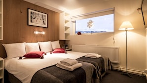 A hotel room with a large bed, two bedside tables, a window with a view, and a floor lamp. - Granen Hotell & Restaurang (Are)