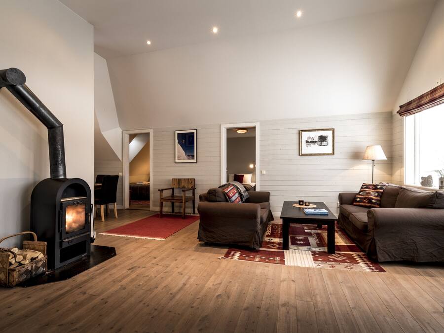 Una sala de estar acogedora con chimenea, suelo de madera y un conjunto de sofás.