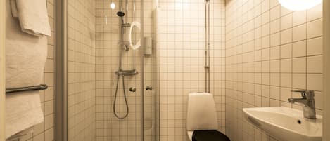 A small, tiled bathroom with a shower, toilet, and sink.