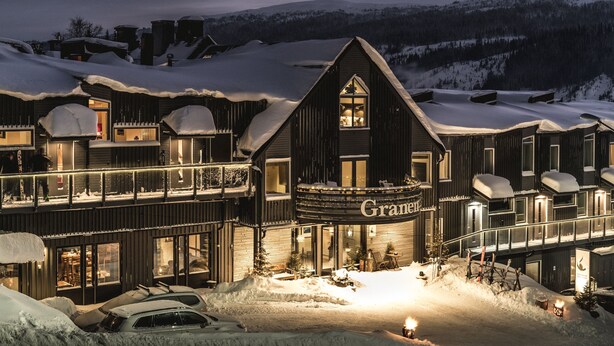 A large, dark-colored building with a prominent 'Grander' sign, multiple balconies, and a snow-covered landscape in the background. - Granen Hotell & Restaurang (Are)