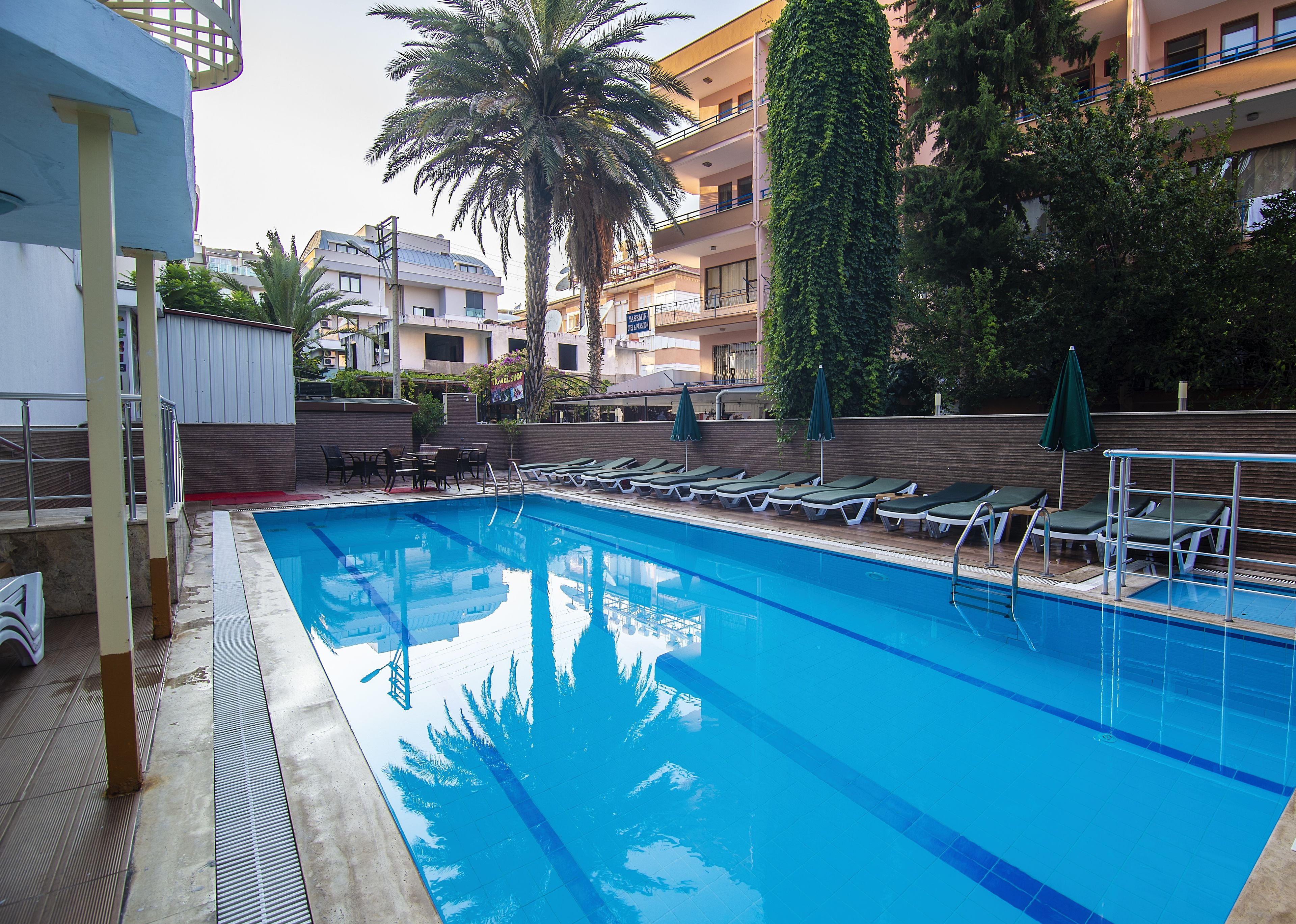 Una piscina al aire libre, sombrillas, sillones reclinables de piscina