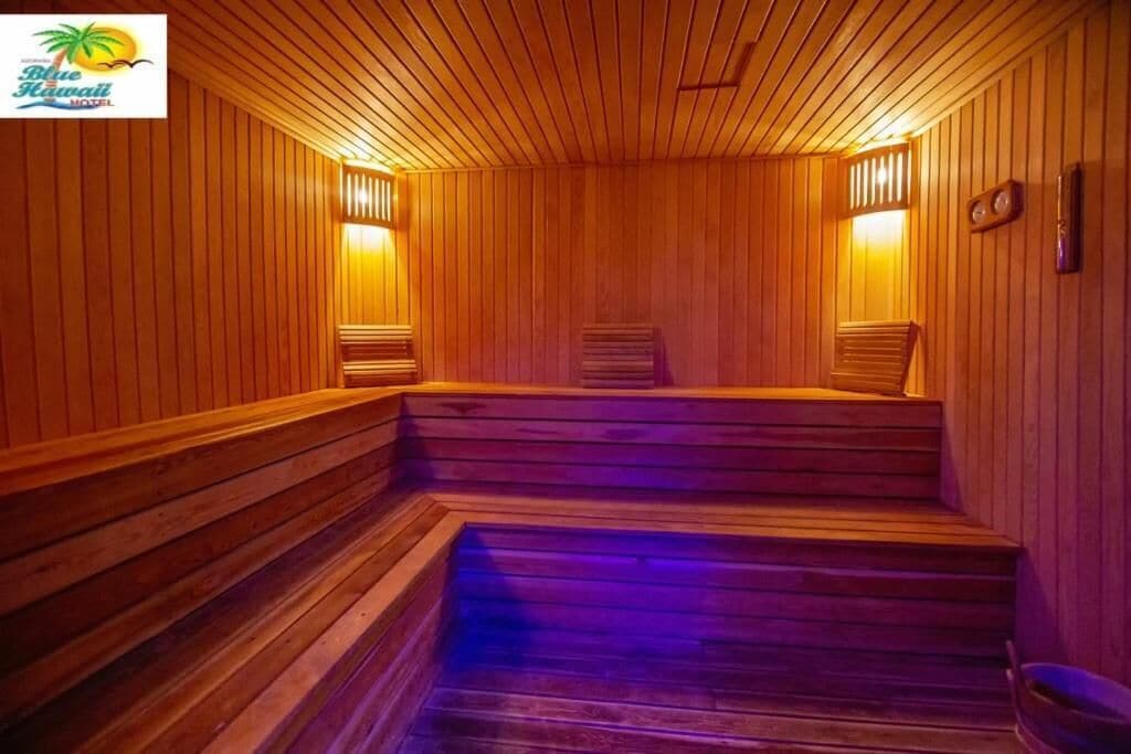 Un sauna en bois, doté de marches et de bancs, éclairé par une lumière chaleureuse.