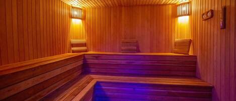 Un sauna en bois, doté de marches et de bancs, éclairé par une lumière chaleureuse.
