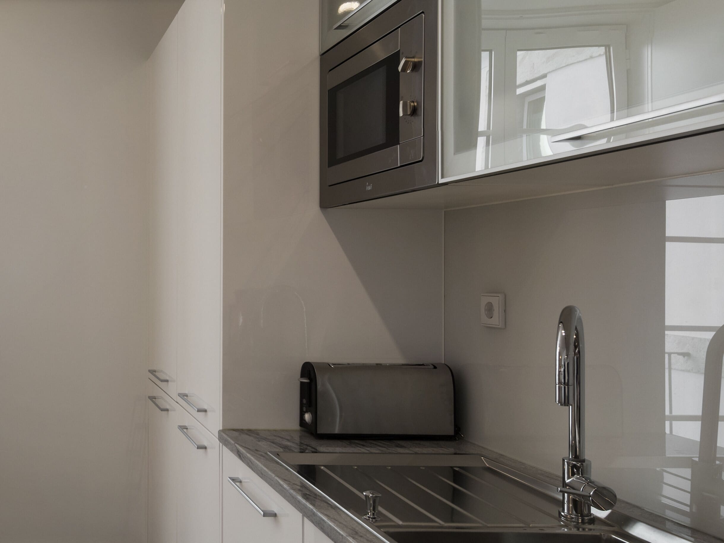 A modern kitchen with a stainless steel microwave, a toaster, and a sink with a faucet.
