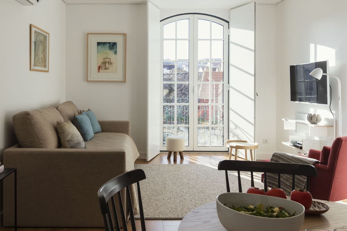 Una sala de estar moderna con un sofá, una mesa de comedor con una ensalada en un bol, un televisor y obras de arte en las paredes.