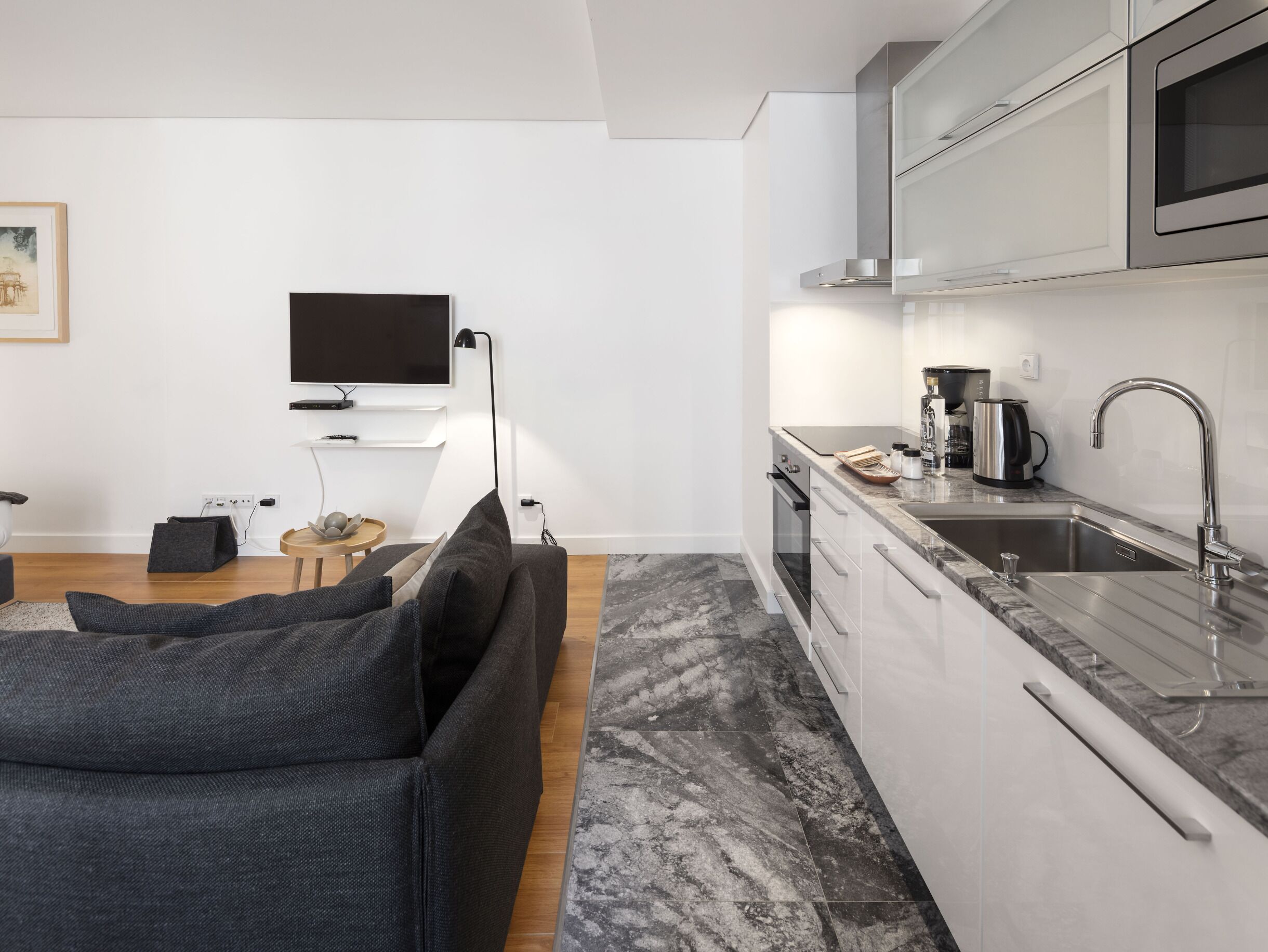 A modern kitchen with a built-in oven, a stainless steel sink, and a microwave.