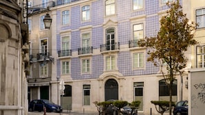 Un bâtiment historique doté d’une façade recouverte de tuiles, de nombreux balcons et d’une cour pavée.