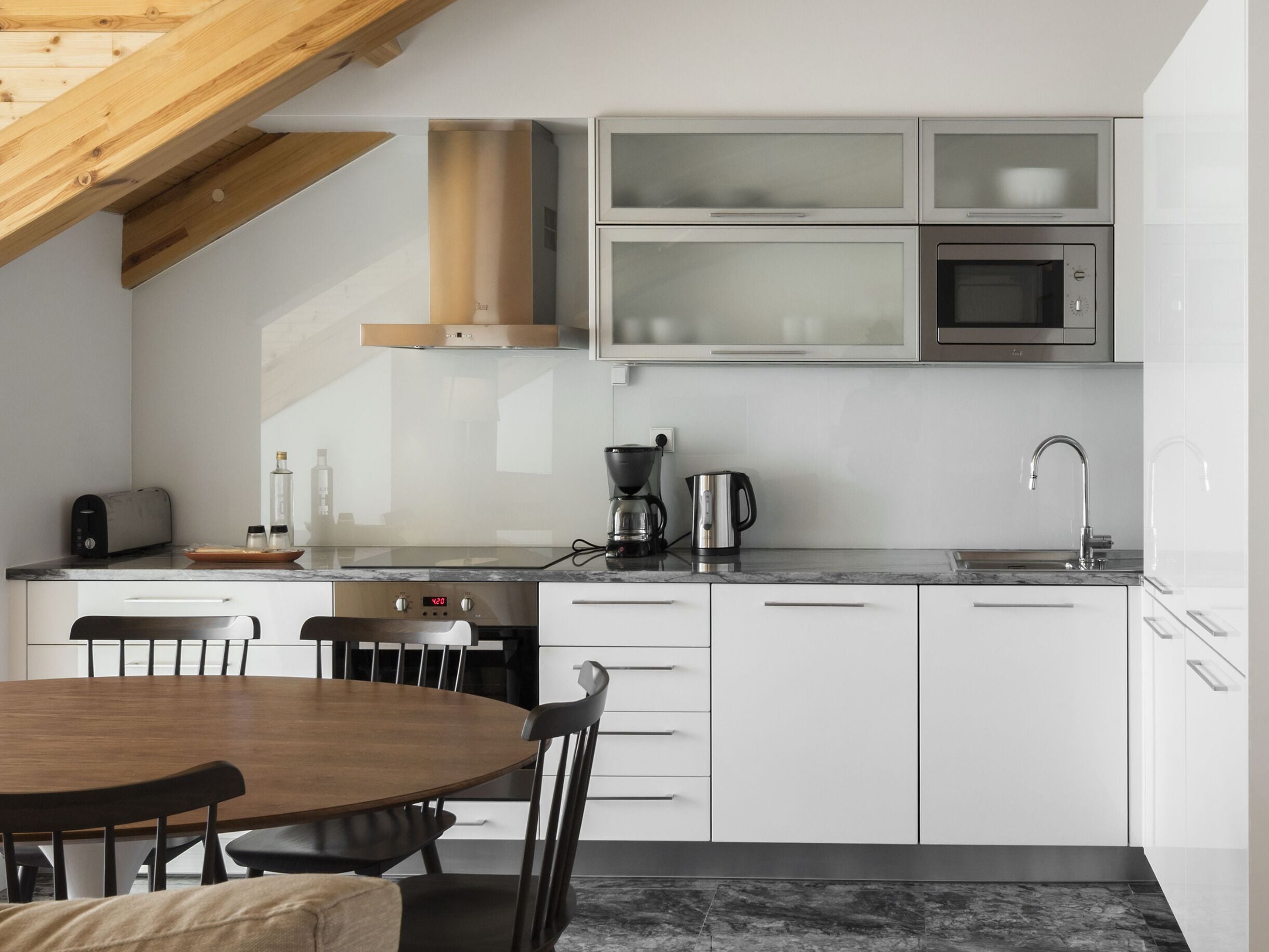 A modern kitchen with white cabinets, a built-in microwave, a coffee maker, and a toaster.