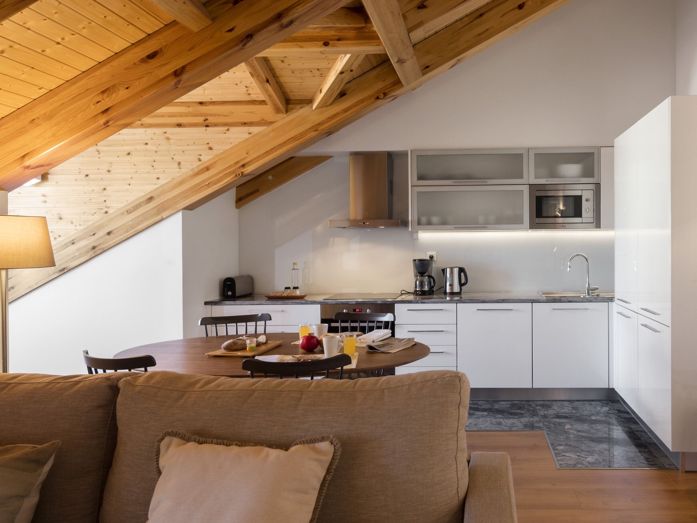 Una cocina moderna con armarios blancos, electrodomésticos de acero inoxidable y techo de madera.