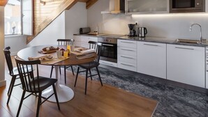 Une cuisine moderne avec des meubles blancs, une table à manger en bois et un four encastré.