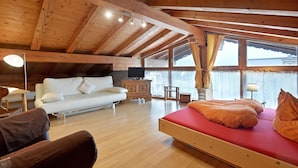 A wooden cabin with a loft bedroom, a sofa, a bed, and a TV. - Landhaus Florian (Sankt Johann in Tirol)