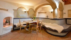 A cozy dining area with a round table, wooden chairs, and a cushioned bench. - Landhaus Florian (Sankt Johann in Tirol)