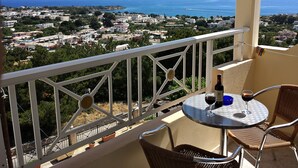 A balcony with a table and chairs overlooking a coastal town. - Stella View Studios (Rhodes)
