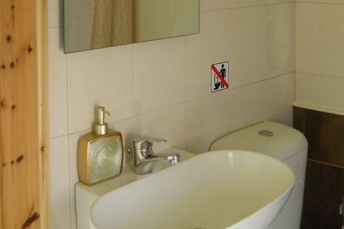 A bathroom with a white sink, a mirror, a towel hanging on the wall, and a toilet.