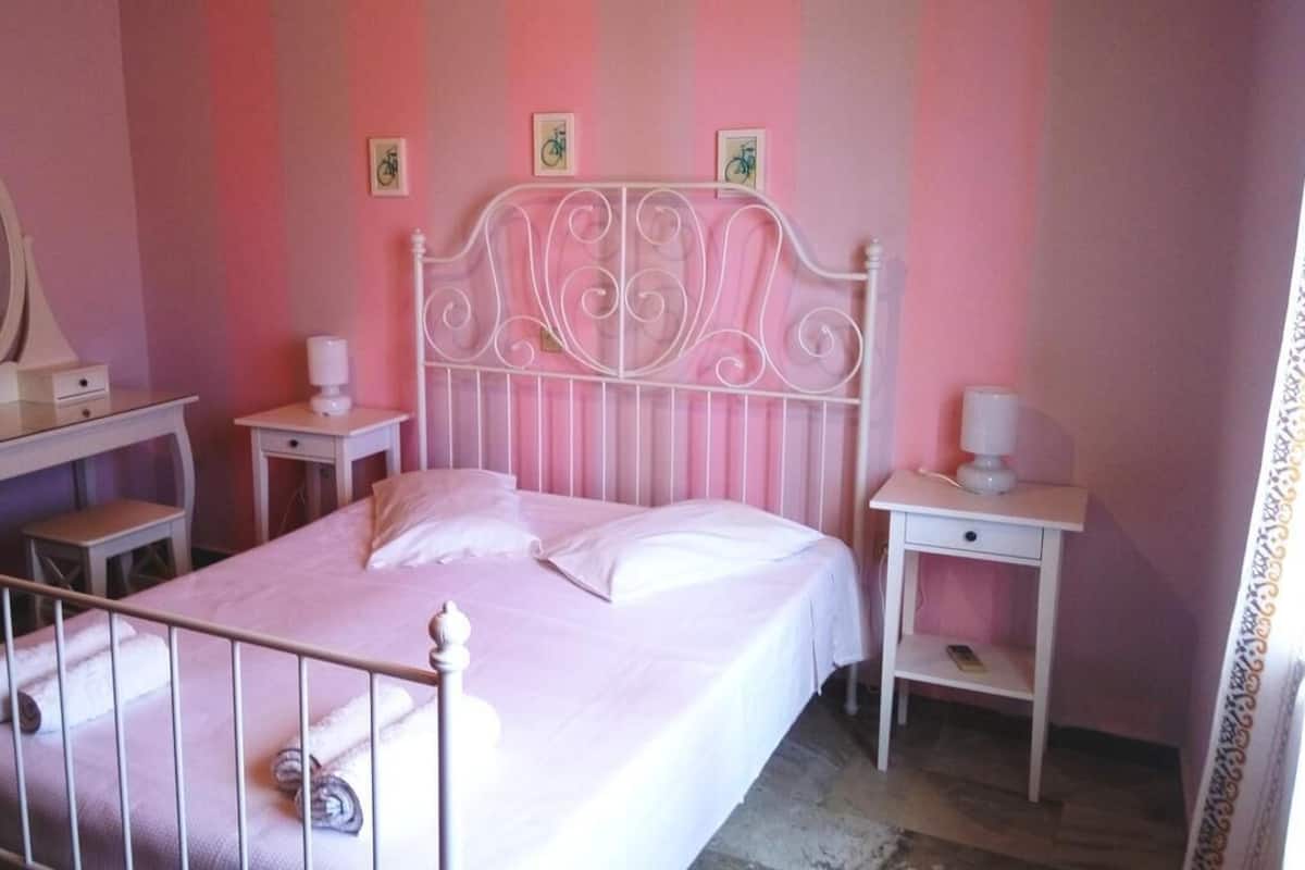 A bedroom with a bed, a nightstand, a dresser, a mirror, and a wall with three framed pictures.