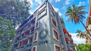 A multi-story hotel with balconies, a prominent logo, and a clear sky. - Treebo Trend Orchard Suites (Bengaluru)