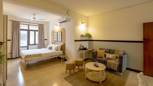 A hotel room with a bed, a sofa, a small table, and a ceiling fan. - Treebo Trend Orchard Suites (Bengaluru)