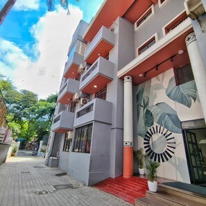 A multi-story hotel with balconies, a large decorative wall, and a red entrance.