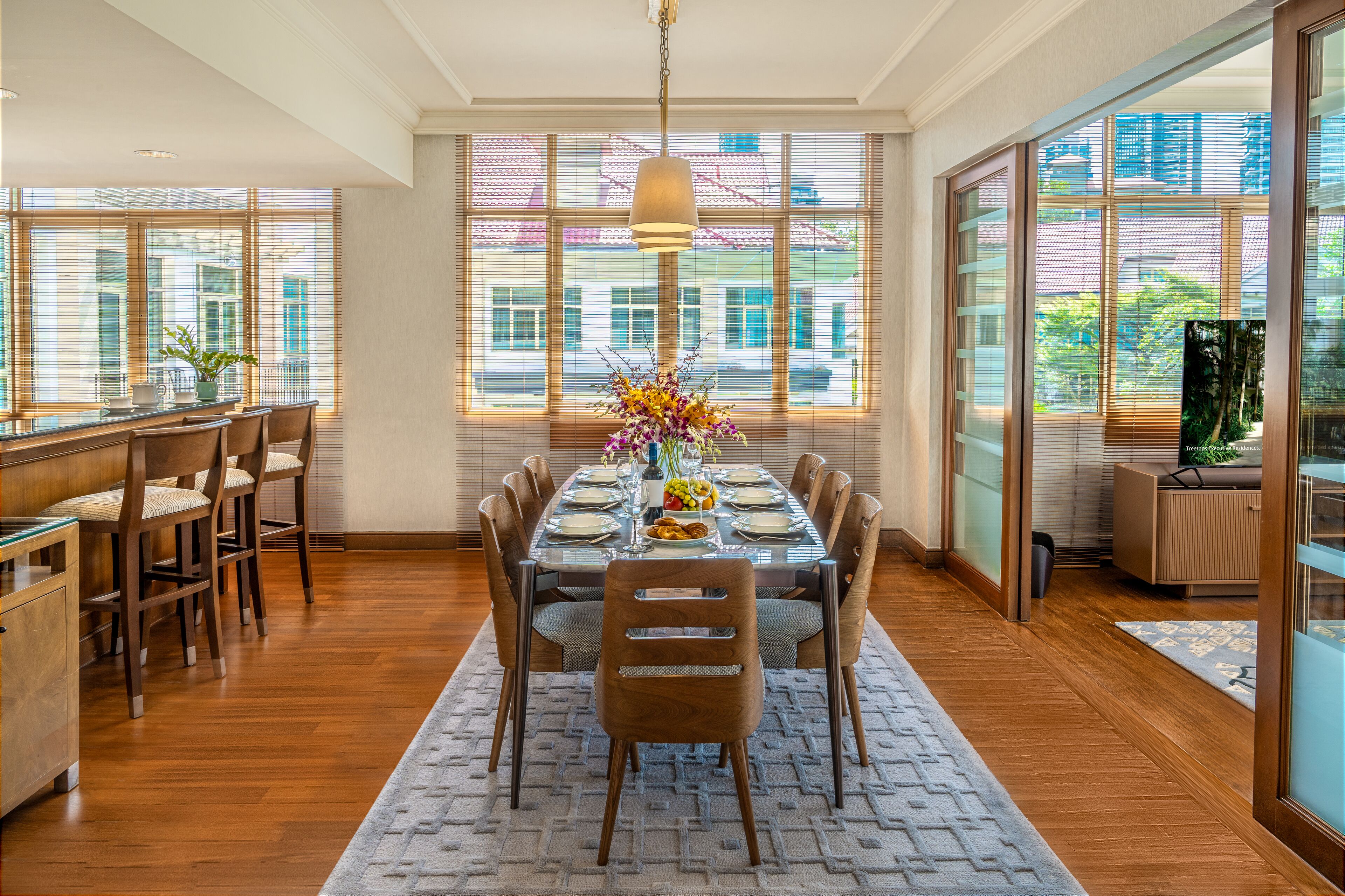 A dining area with a long table, chairs, and a vase of flowers.