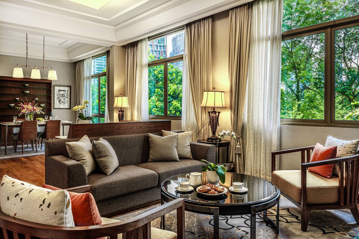 A spacious living room with a sofa, armchairs, a coffee table, and a dining area with chairs and a table.