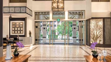 A hotel lobby with a reception desk, framed certificates, a chandelier, and a wooden reception desk.