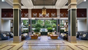 A spacious lobby with a central seating area, large pillars, and a view of a waterfall and greenery outside. - Treetops Executive Residences (Singapore)