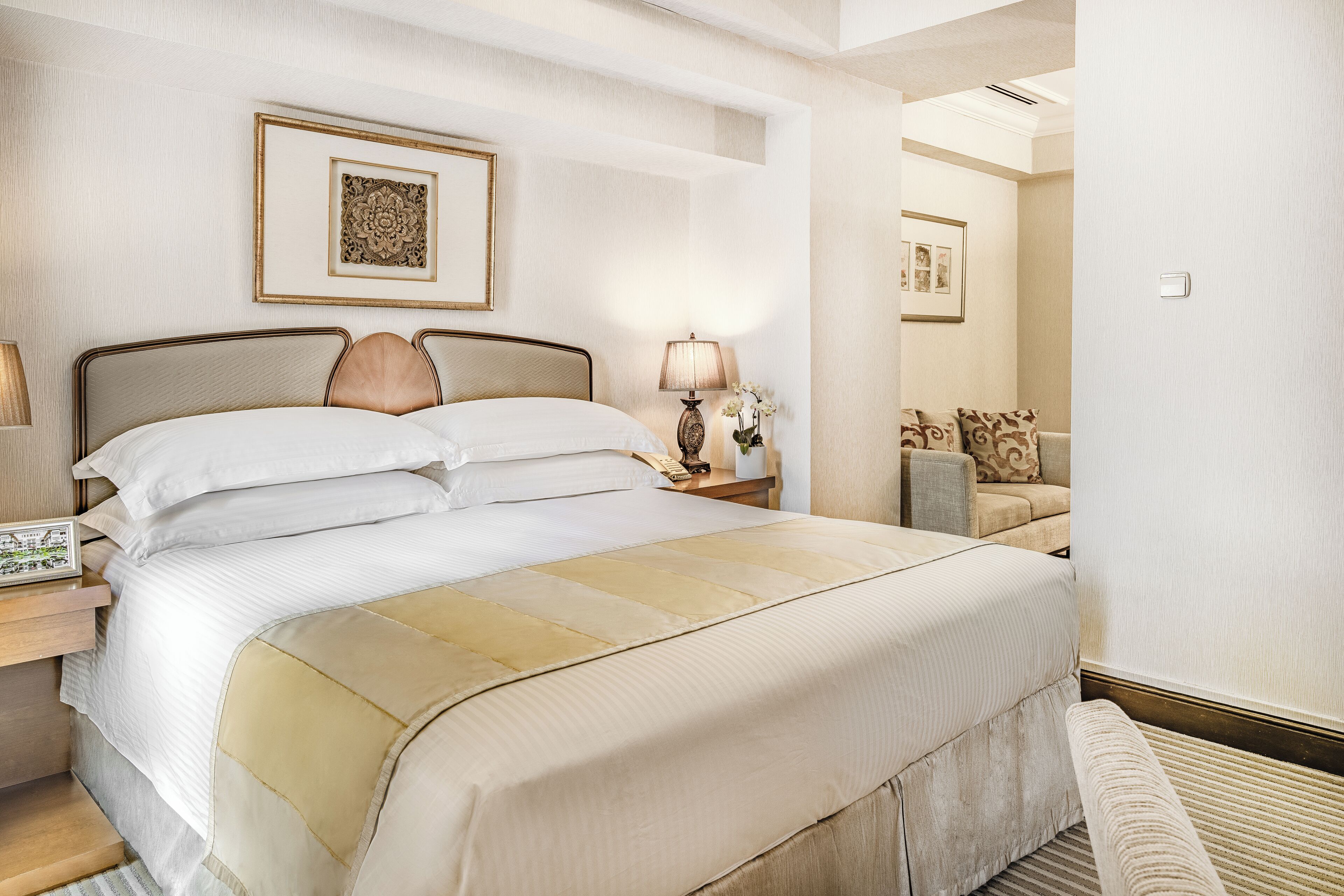 A neatly made bed with a headboard, a bedside lamp, and a framed picture on the wall.