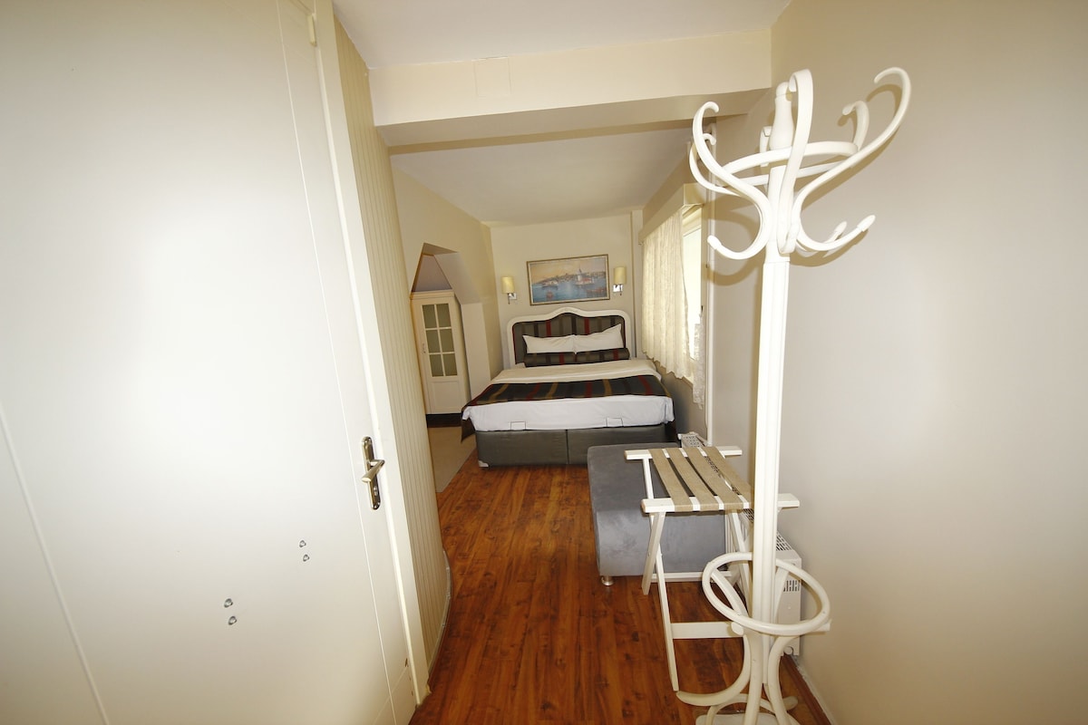 A narrow hallway with a bed, a bench, and a coat rack.