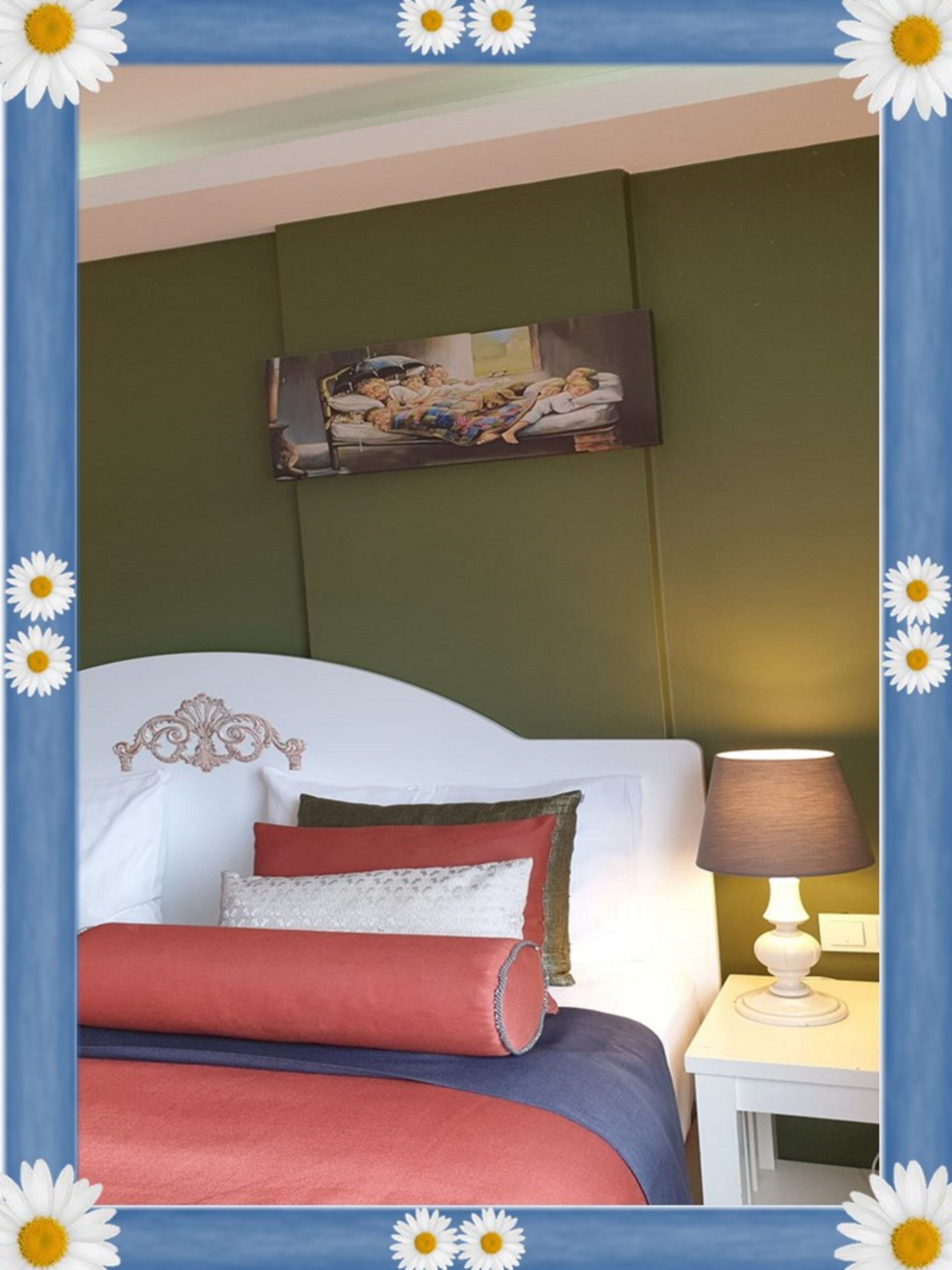 Um quarto com cama, travesseiros, mesa de cabeceira, abajur e um quadro na parede.