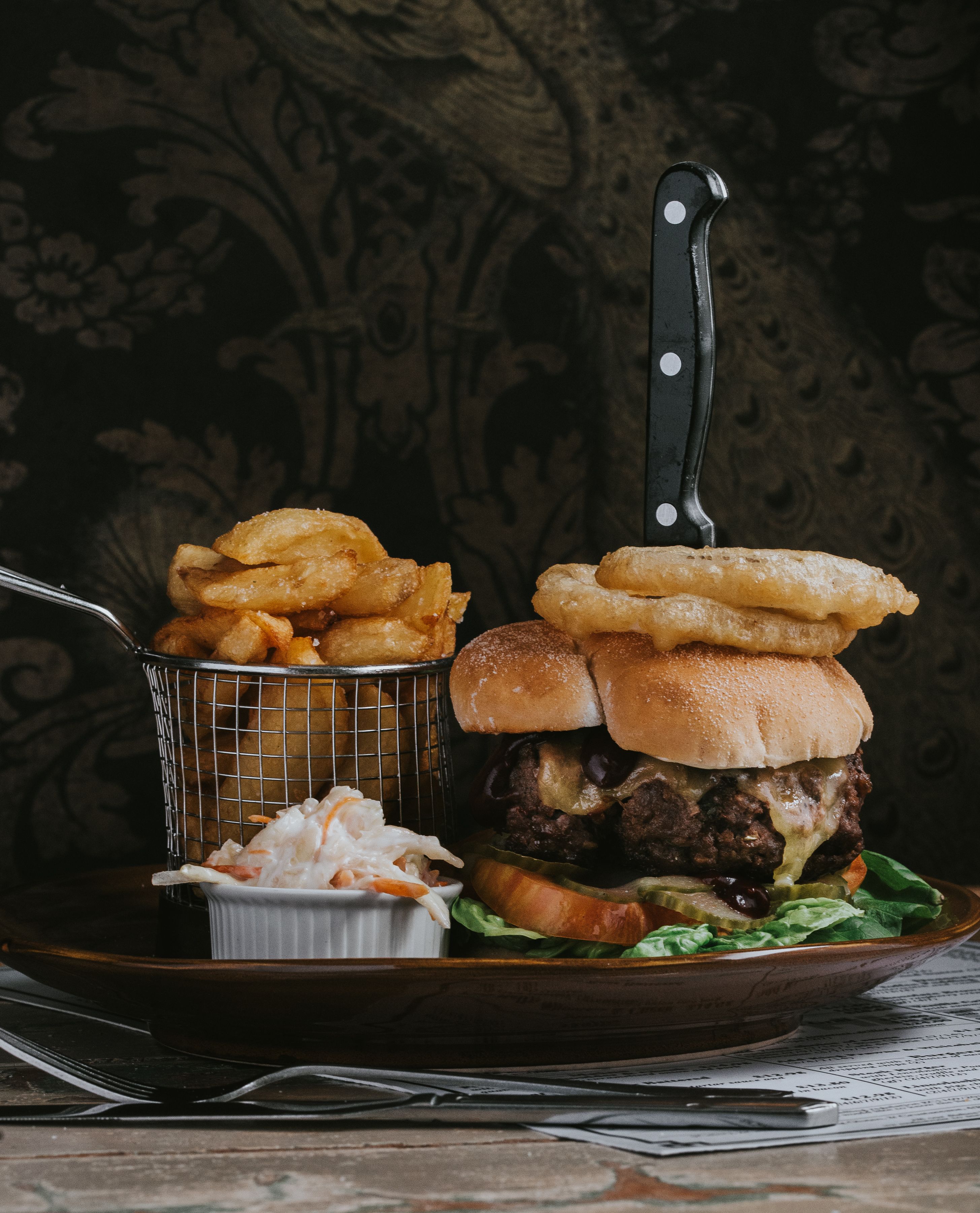A burger with fries and coleslaw on a plate.