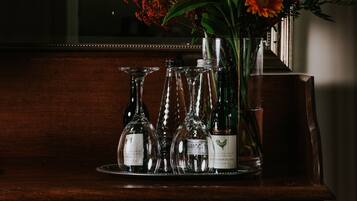 A wooden dresser with a mirror, a vase of flowers, and several wine bottles.