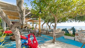 Ein Restaurant direkt am Strand mit Terrassenplätzen, einem Spielbereich für Kinder und Meerblick.