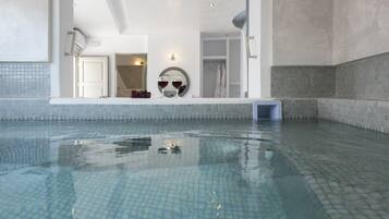 A large indoor swimming pool with clear blue water, a tiled floor, and a white interior.