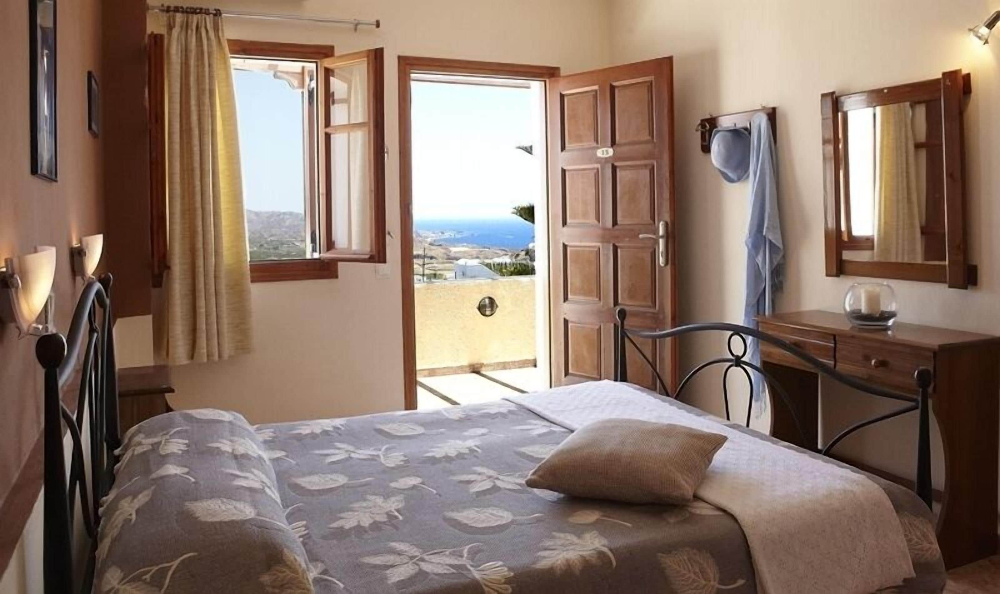 Un dormitorio con cama, cómoda, espejo y vistas al exterior.