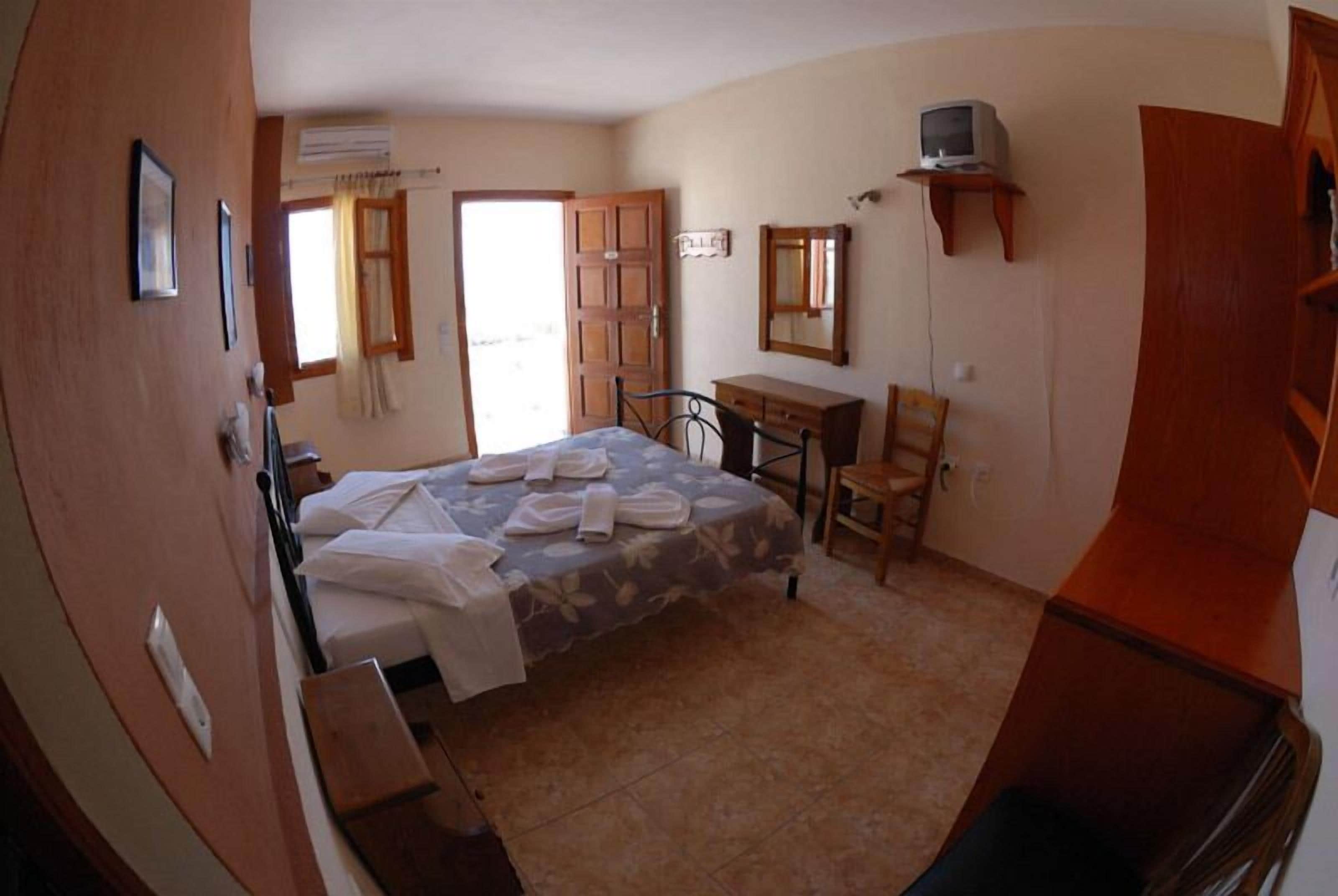 A bedroom with a bed, a desk, a chair, a television, and a wardrobe.