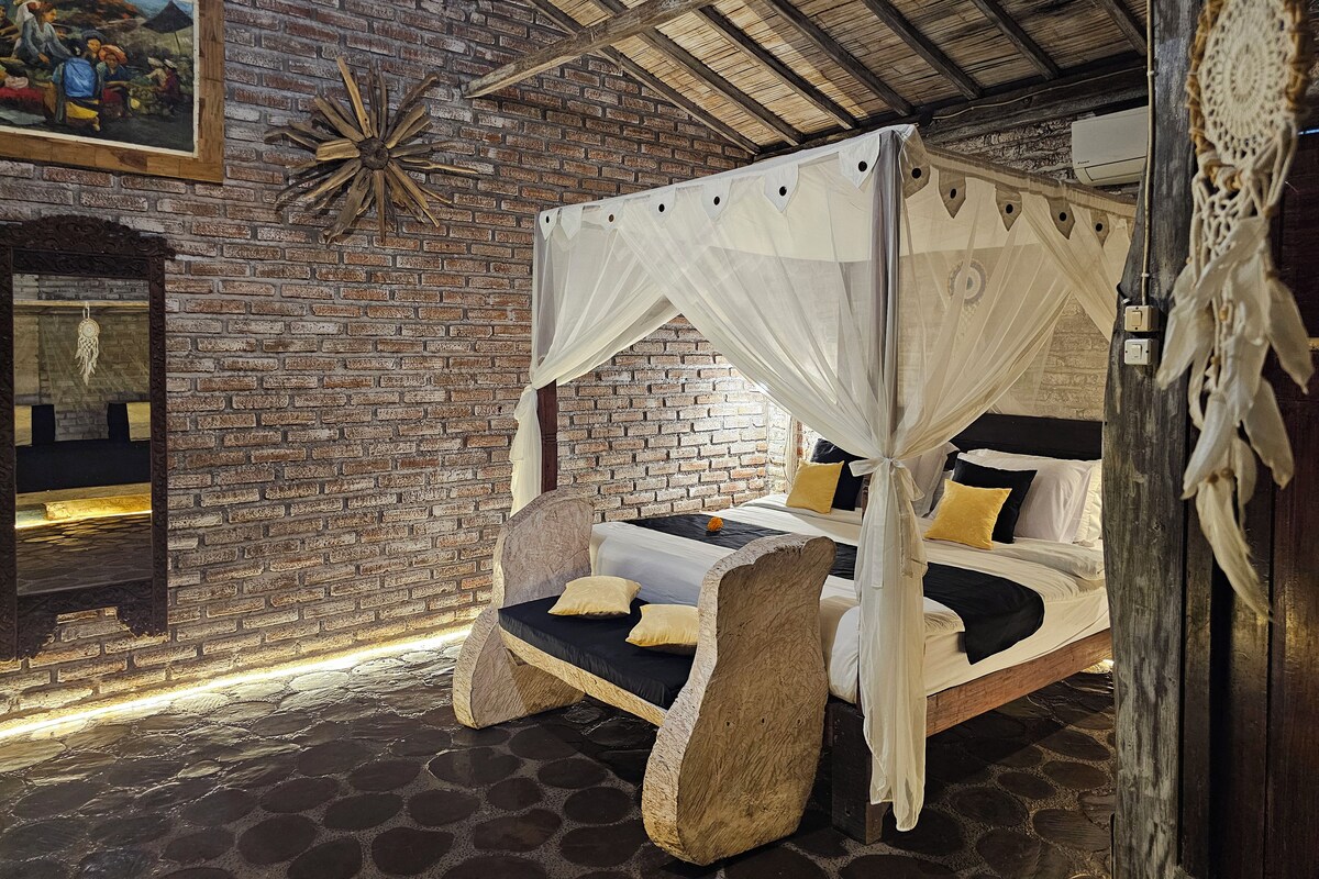 A rustic room with a brick wall, a bed with a canopy, and a decorative mirror.