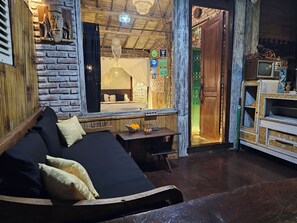 A room with a bed, a table with flowers, a television, and a rustic brick wall. - Santhiku Hotel & SPA (Banjar)