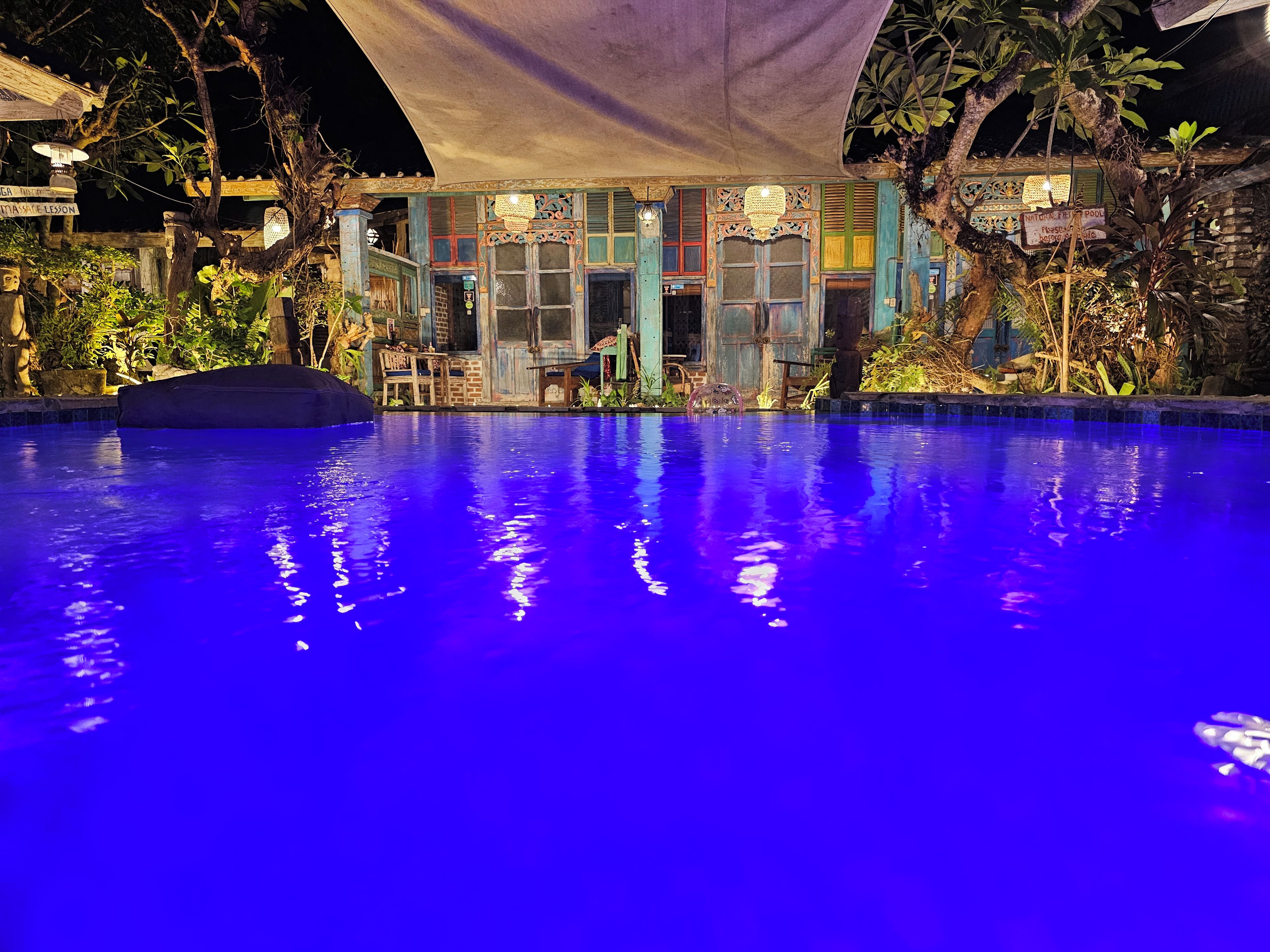 Vista nocturna de una piscina con un edificio al fondo.